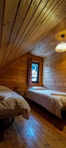 a bedroom with two beds in a wooden cabin at Chale do Avô Chico Penhas da Saúde in Penhas da Saúde