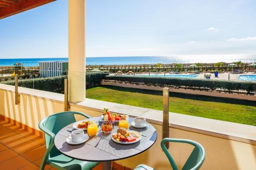 a table with food on a balcony with a view of the beach at Pestana Alvor Beach Villas Seaside Resort in Alvor