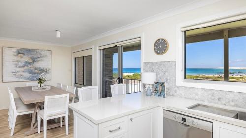 a kitchen and dining room with a table and a clock at Absolute Birubi Beachfront in Anna Bay