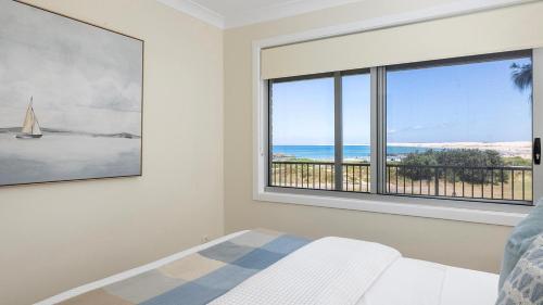 a bedroom with a window with a view of the ocean at Absolute Birubi Beachfront in Anna Bay