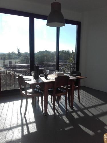 une table de salle à manger avec des chaises et une grande fenêtre dans l'établissement Chambre d'hôtes avec cuisine commune - 5 mns de Narbonne, à Cuxac-dʼAude