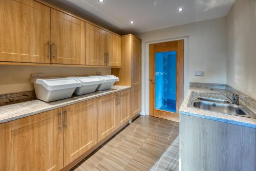 a kitchen with wooden cabinets and a sink at The Fairways House in Glenrothes
