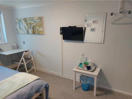 a room with a bed and a table and a refrigerator at Double bedroom with ensuite wet room, incl breakfast, in Woking in Woking