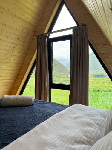 a bed in a room with a large window at Cottage GORDA Kazbegi in Akhalts'ikhe