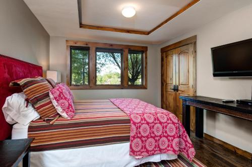 a bedroom with a bed with pink sheets and a tv at Abode at Teton Manor in Jackson