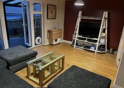 a living room with a couch and a tv at Entire Family Entertainment Holiday Home - 3 x Floors - Free Parking - Games Room - Private Garden - Workspace and Wifi 112mb - Self Check-in in Ashford