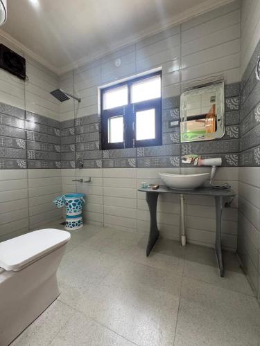 a bathroom with a sink and a toilet and a window at Hotel Shuhrah-I-Afaq - Near Srinagar Airport in Baghwānpur
