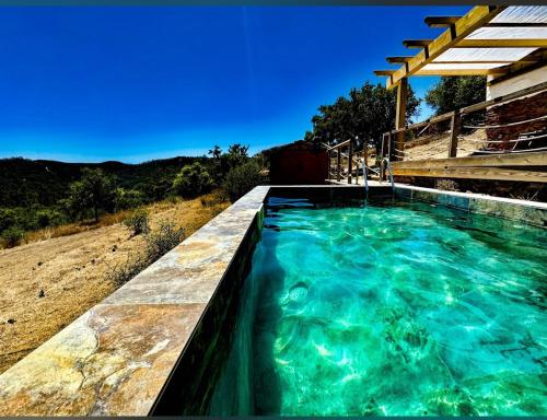 a swimming pool with blue water in a field at Herdade da Maceira in São Luis