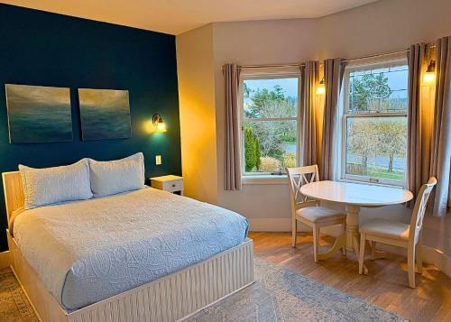 a bedroom with a bed and a table and window at The Edenwild Boutique Inn in Lopez