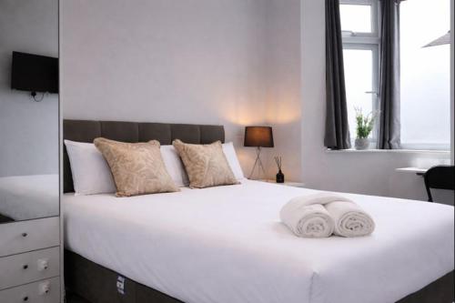 a large white bed with two towels on it at Walton Suites in Watford