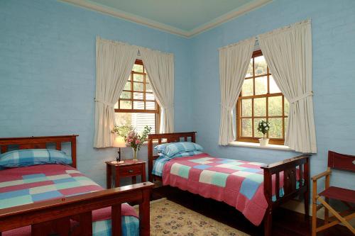 two beds in a room with two windows at Amanda's Cottage 1899 in McLaren Vale