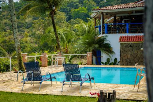two blue chairs sitting next to a swimming pool at VELINN Pousada 8 Ilhas in Ilhabela
