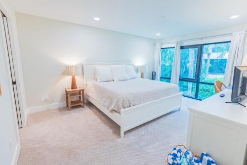 a white bedroom with a bed and a window at Breezy Beachside Views! Heated Pool & Pickleball! in Holmes Beach