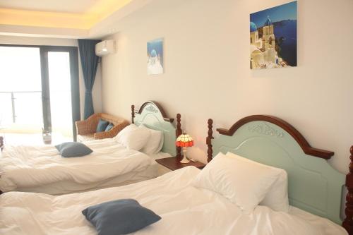 a bedroom with three beds with pillows on them at Coast-Inn Hailing Island in Yangjiang