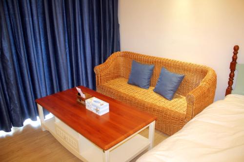 a living room with a wicker couch and a table at Coast-Inn Hailing Island in Yangjiang