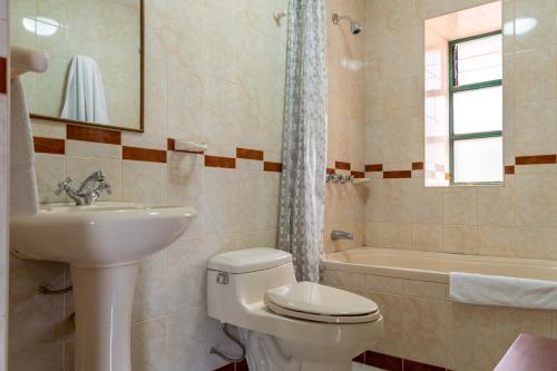 a bathroom with a toilet and a sink and a tub at Hospedaje La Florida in Urubamba