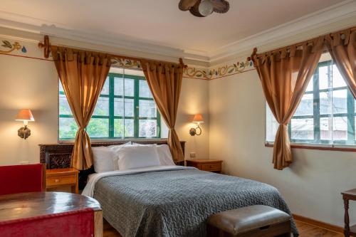a bedroom with a bed and two windows at Hospedaje La Florida in Urubamba
