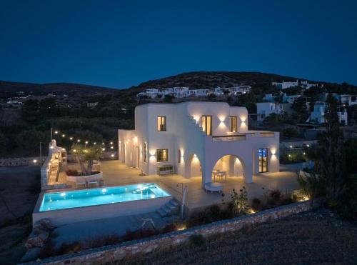 a large white house with a swimming pool at night at OceanLight Horizon - luxury Villa with private pool in Nea Cryssi Akti