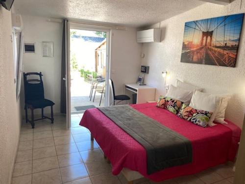 a bedroom with a large bed with a red blanket at LOGIS Hôtel Restaurant La Chaumière in Marseillan