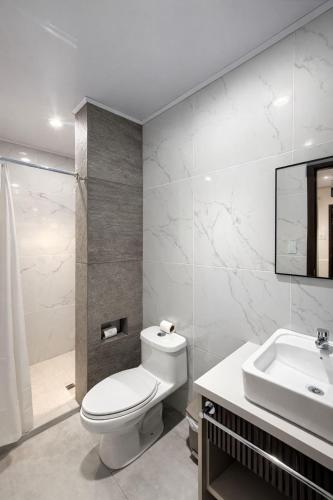 a white bathroom with a toilet and a sink at Hotel Madrigal in Portoviejo