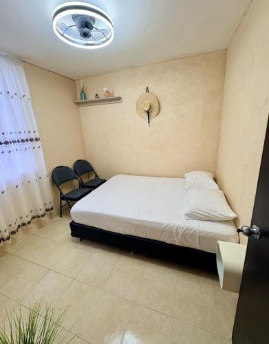 a bedroom with a bed and two chairs in it at Departamento tranquilo Huatulco in Santa Cruz Huatulco