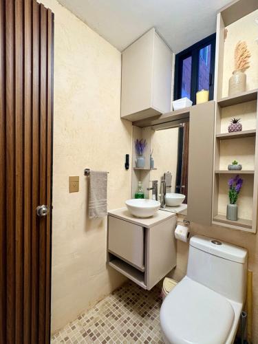 a bathroom with a white toilet and two sinks at Departamento tranquilo Huatulco in Santa Cruz Huatulco