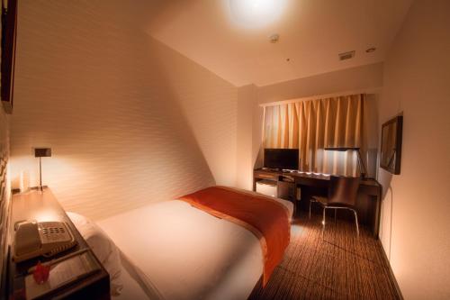 a hotel room with a bed and a desk with a computer at Hotel Hokke Club Shonan Fujisawa in Fujisawa