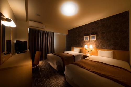 a hotel room with two beds and a television at Hotel Hokke Club Shonan Fujisawa in Fujisawa