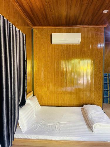 a bed in a room with a wooden wall at Farm Tân Tiến in Ấp Bình Thạnh
