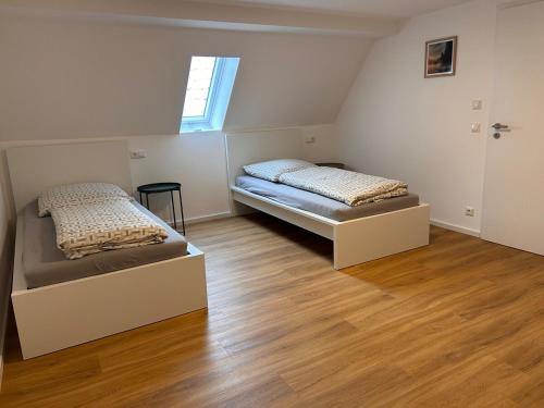 two beds in a room with wooden floors and a window at Groß Höpper in Albertshofen