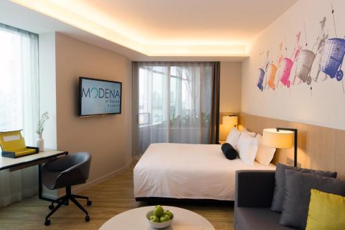 a hotel room with a bed and a desk at Modena by Fraser Bangkok in Bangkok