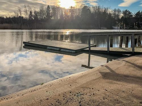 a dock on a lake with the sun reflecting in the water at Holiday Home Jarsala by Interhome in Töfsala