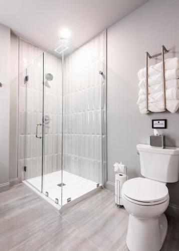 a white bathroom with a shower and a toilet at Hollyhock Suite 403 in Louisville