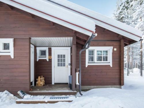 a small wooden house with a white door in the snow at Holiday Home Albatrossi by Interhome in Levi