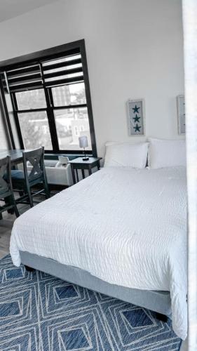 a bedroom with a large white bed and a table at Stylish Studio Apt-Outside NYC in West New York