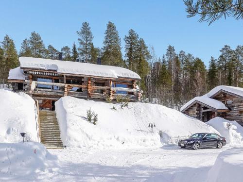 a car parked in the snow in front of a log cabin at Holiday Home Sallanhelmi e2 by Interhome in Salla
