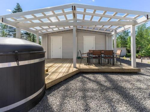 a pergola with a table and chairs on a deck at Holiday Home Valonsäde by Interhome in Valkeala