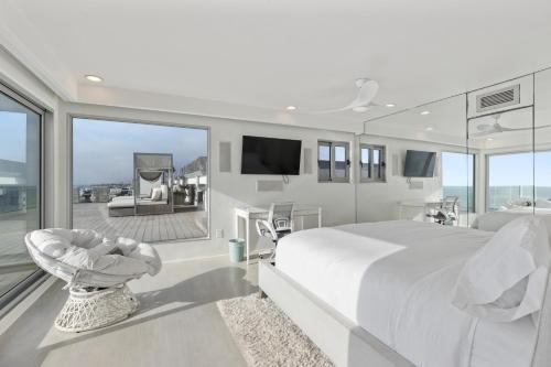a white bedroom with a large bed and a balcony at Encinitas Shores - Beachfront, Ocean View & Patio in Encinitas