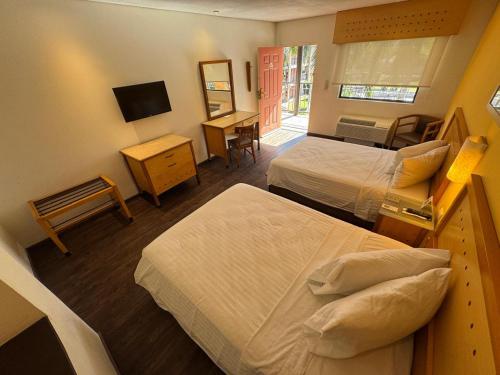 a hotel room with two beds and a television at Hotel Colonial Hermosillo in Hermosillo