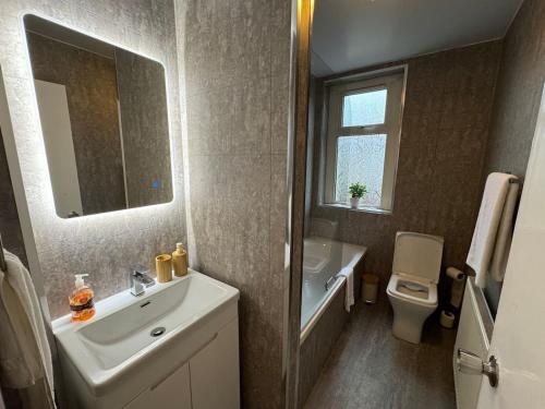 a bathroom with a sink and a toilet and a mirror at Modern 2BR Cottage Flat in Bellshill