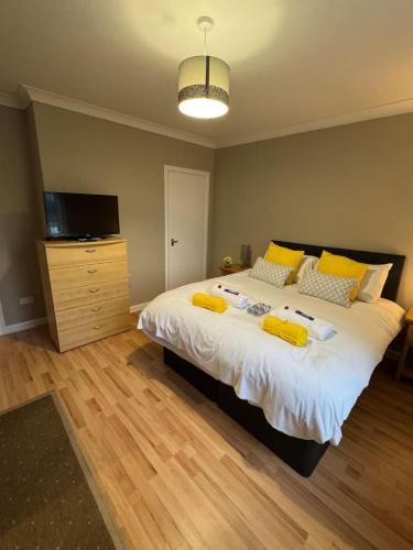 a bedroom with a large bed with yellow pillows at Modern 2BR Cottage Flat in Bellshill