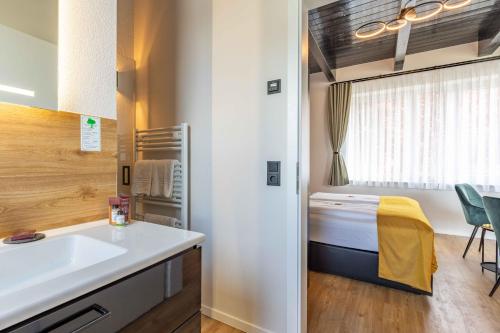 a small bathroom with a sink and a bed at LÜTTES LOFT Boutique Hotel in Eckernförde