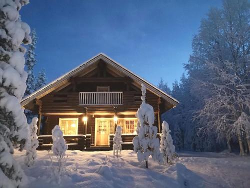 a log cabin in the snow with lights on at Holiday Home Luppokero by Interhome in Salla