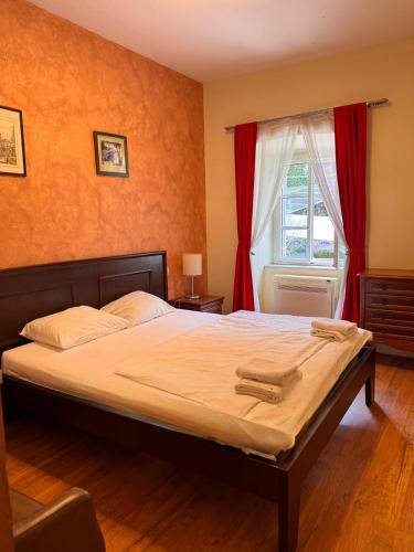 a bedroom with a bed with red curtains and a window at Miramare Seaside Aparts in Kotor