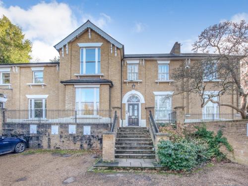a large brick house with stairs in front of it at Gated Mansion Apartment- Stylish, Quiet & Secure in Bromley