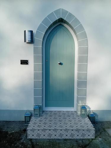 a blue door on a building with two lights at River View at Silver River in Cadamstown