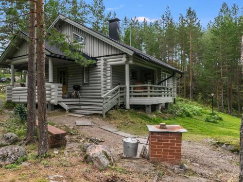 a cabin in the woods with a dog sitting on the porch at Holiday Home Lahukka by Interhome in Hurissalo