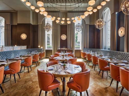 a restaurant with tables and chairs and chandeliers at Sofitel London St James in London
