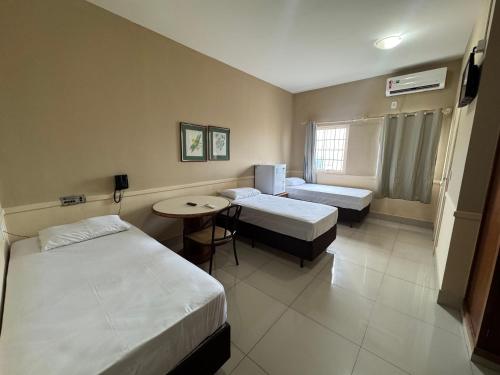 a hotel room with two beds and a table at Hotel Executive Uberaba in Uberaba