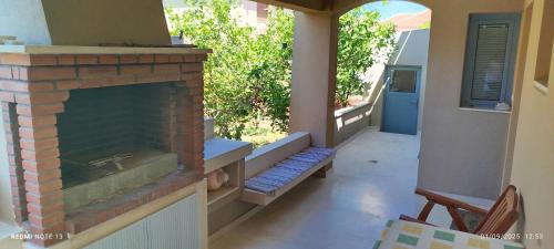 a porch with a brick fireplace with a bench at Zach's house in Nea Roda